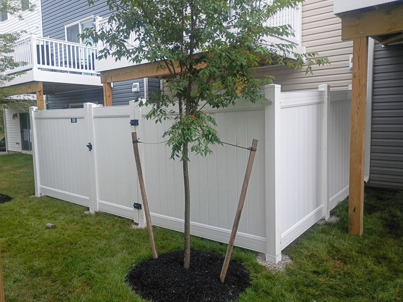 White vinyl privacy fence turning the corner of a house with a gate in line