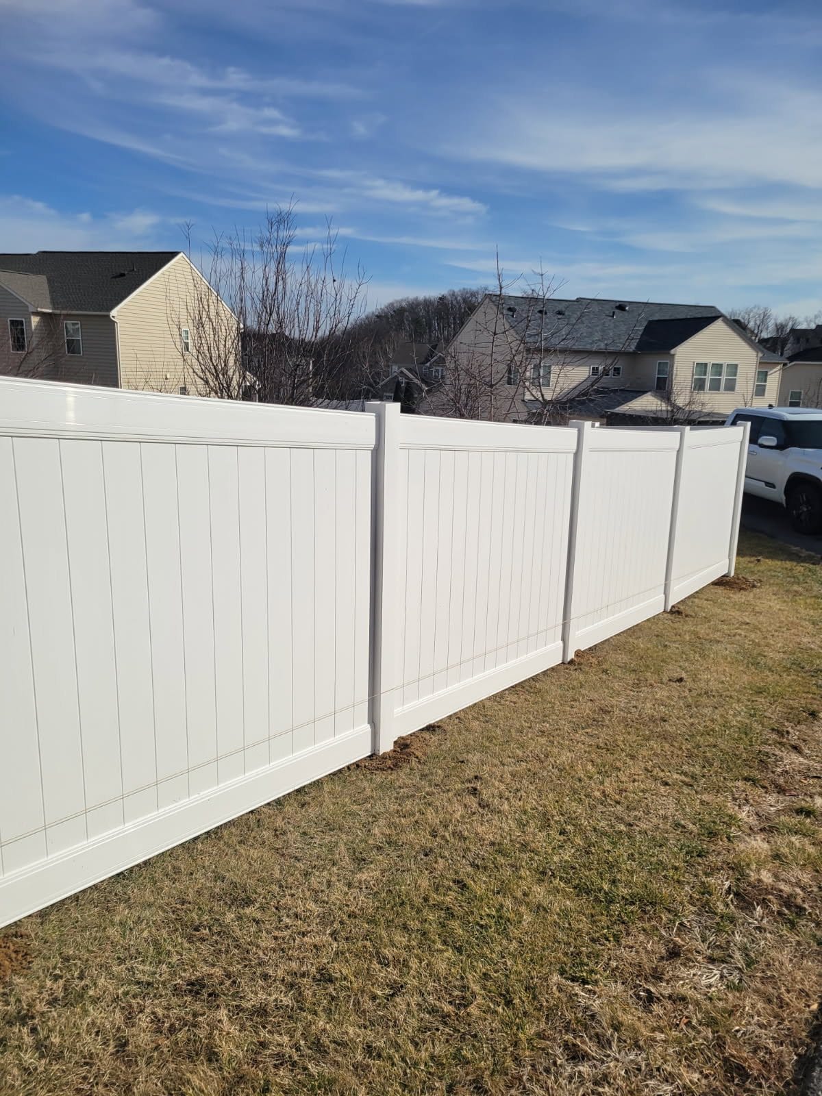 White vinyl privacy fence run along a back yard